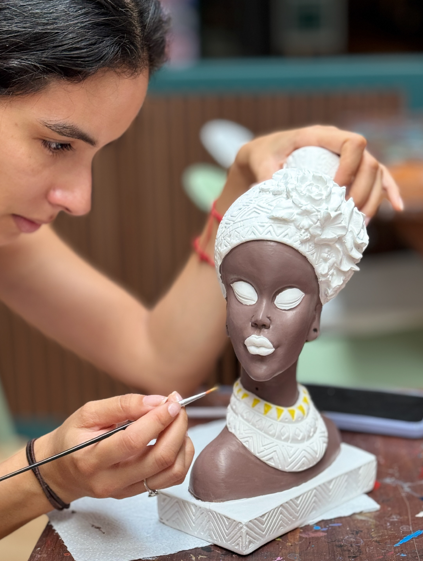 Persona pintando una figura en COCOART Studio, mesa compartida, luz natural